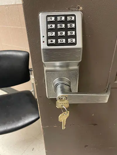 A key pad lock with keys attached to it.