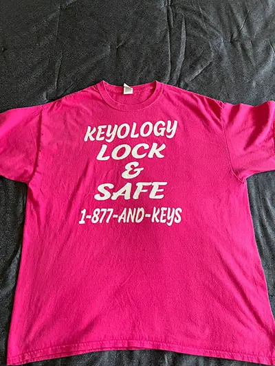 A pink t-shirt that says keyology lock and safe.