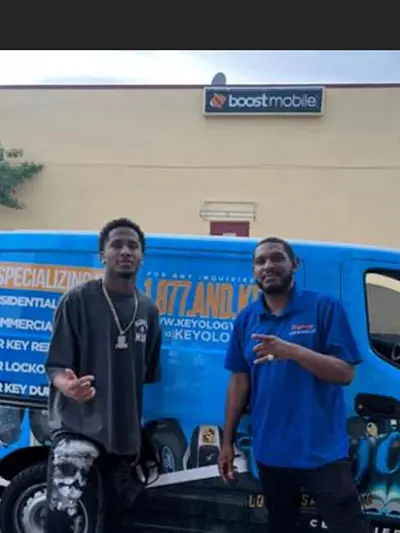 Two men standing in front of a blue truck.