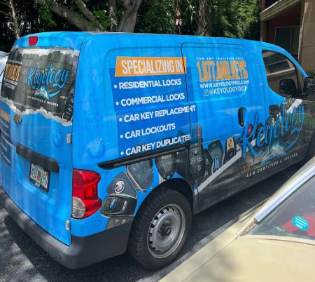 A van with blue and black wrap on the side of it.